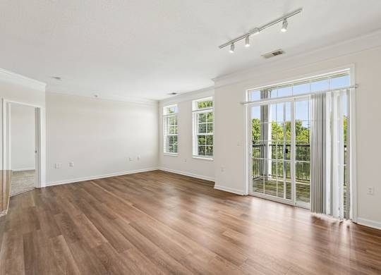 A room with wooden floors and a sliding glass door leading to a backyard.