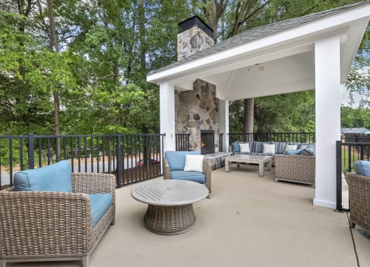 a covered patio with wicker furniture and a fireplace