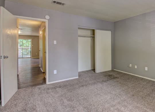 an empty living room with carpet and a door to a hallway