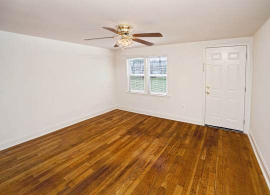 A room with a ceiling fan and wooden flooring.