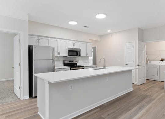 a white kitchen with a large island and stainless steel appliances at The Charleston, Columbus, OH