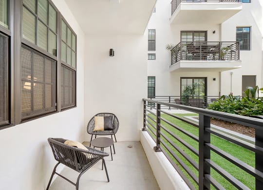 a balcony with two chairs and a grassy area