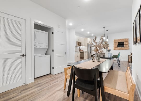a dining area with a table and chairs and a kitchen with a washer and dryer