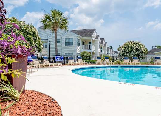 A swimming pool in a residential area with houses in the background.