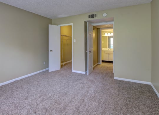 a bedroom with a carpeted floor and a door to a bathroom