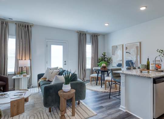 A modern kitchen with a green couch and a dining table at The Mark Townhomes Apartments, Harrisonburg, VA