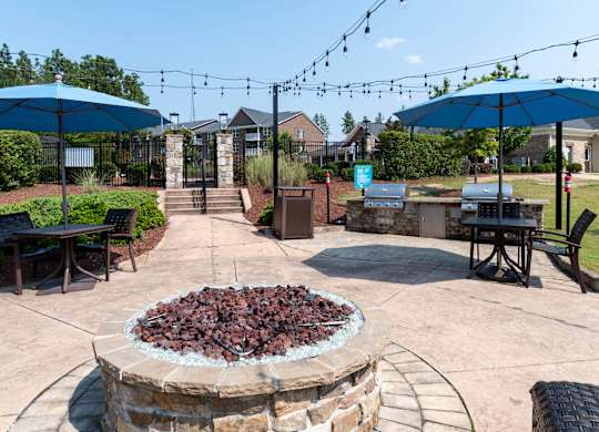 A patio with a fire pit and umbrellas.