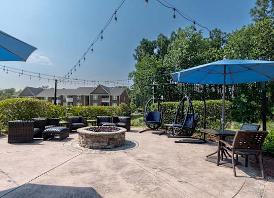 A patio with a fire pit and chairs.