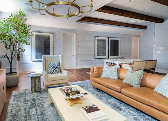 A living room with a brown couch and a chandelier.
