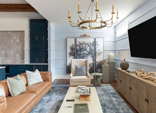 A living room with a brown leather couch and a chandelier.
