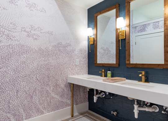 A bathroom with a white sink and a wallpapered wall.