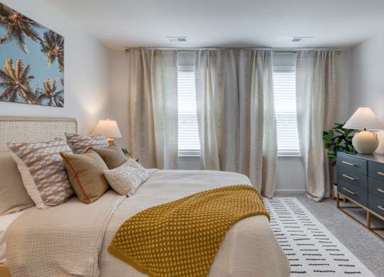 A bedroom with a large bed, a dresser, and a mirror at The Mark Townhomes Apartments, Harrisonburg, VA, 22801