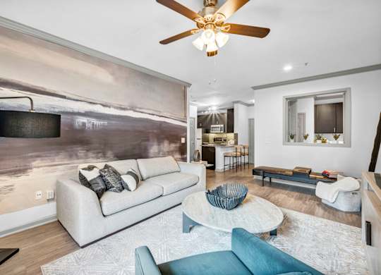 A modern living room with a large painting on the wall and a ceiling fan.