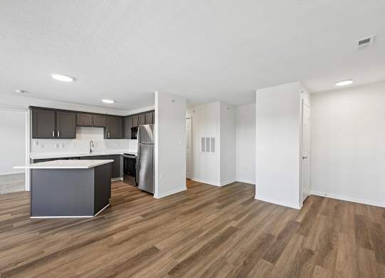 A kitchen with a refrigerator, sink, and cabinets.