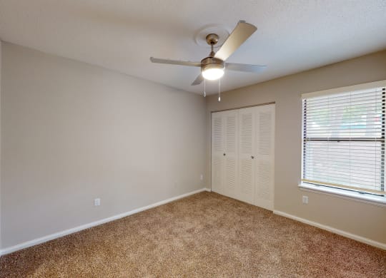 a bedroom with a ceiling fan and window