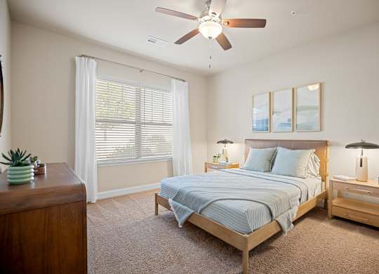 A bedroom with a bed, nightstand, and a ceiling fan.