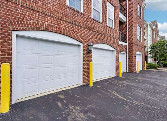 A row of garage doors in front of a brick building.