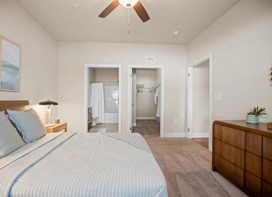 A bedroom with a large bed and a ceiling fan.