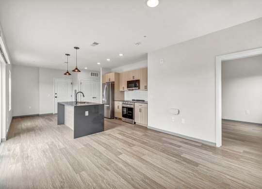 A spacious kitchen and living room with wooden flooring and modern appliances.