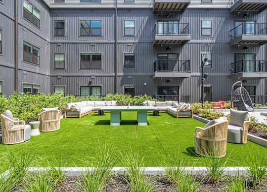 A large grassy area with chairs and tables in front of a building.
