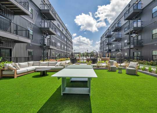 A large grassy area with a table and chairs in the middle of it.
