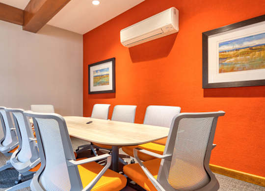 A conference room with a table, chairs, and two framed pictures on the wall.