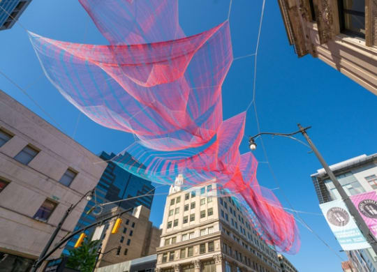 a large red and blue jellyfish sculpture hanging from a wire in the middle of a cityat Preston Centre, Ohio, 43215