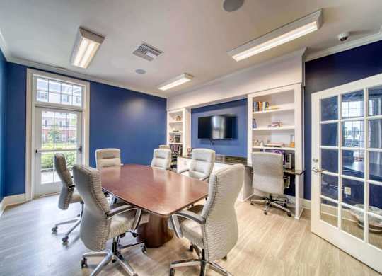 A conference room with a large table surrounded by chairs.