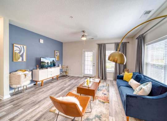 A living room with a blue couch and a wooden floor.