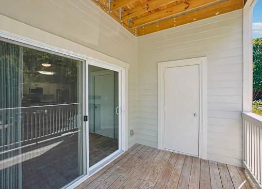 A balcony with a glass door and a white door.