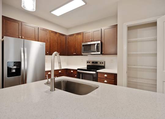 A kitchen with a stainless steel refrigerator and microwave above the stove.