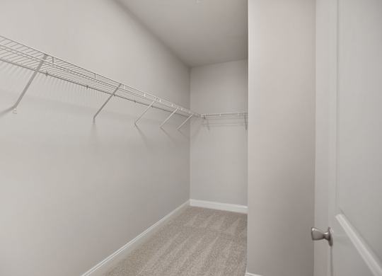 A white hallway with a carpeted floor and a door on the right.