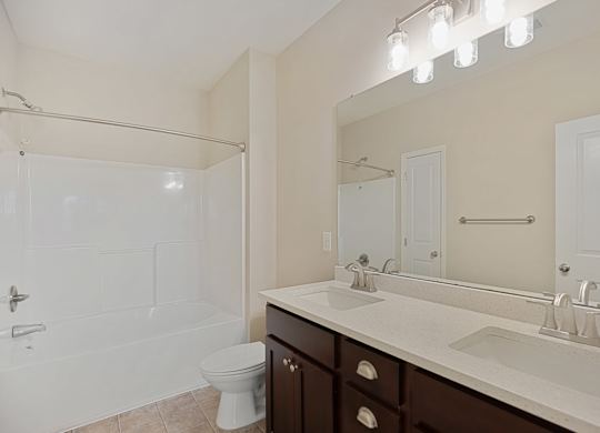 A white bathroom with a toilet, sink, and shower.