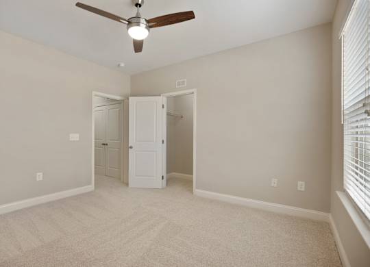 A room with a ceiling fan and carpeted floor.