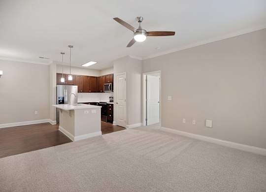 A spacious living room with a kitchen in the background.