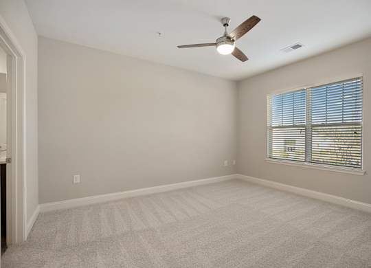 A room with a ceiling fan and a window with blinds.