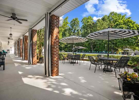 A patio with tables and chairs and umbrellas.