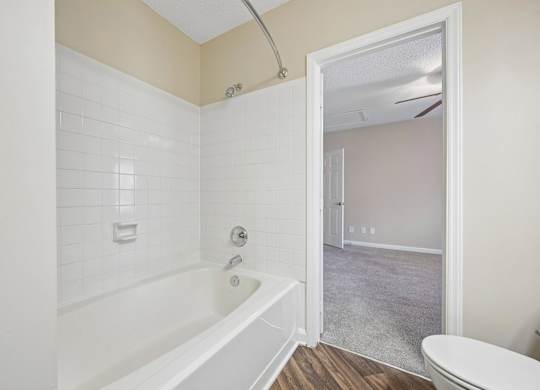 A white bathroom with a tub and toilet.