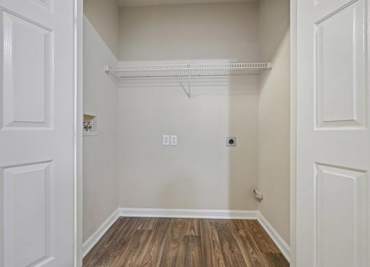 A white closet with a wooden floor and a white door.