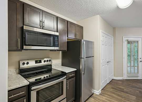 A kitchen with a stove, oven, microwave, and refrigerator.