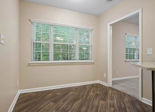 A room with wooden floors and a window with green blinds.