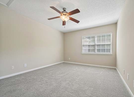 A room with a ceiling fan and carpeted floor.