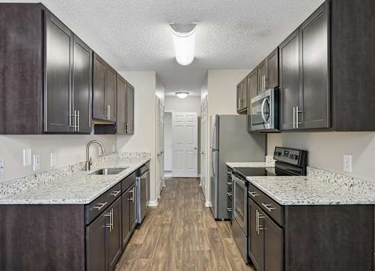 A kitchen with dark brown cabinets and a white counter top.