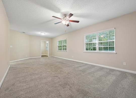 A room with a ceiling fan and carpeted floor.