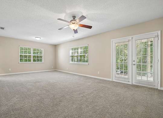 A room with a ceiling fan and two windows with blinds.
