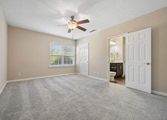 A room with a ceiling fan and carpeted floor.