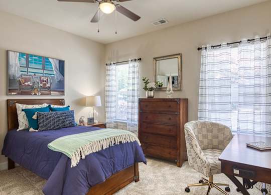 A bedroom with a bed, chair, and painting on the wall.