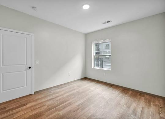 A room with a white door and a window with blinds.