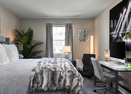 A bedroom with a large bed, a desk with a computer, and a chair.