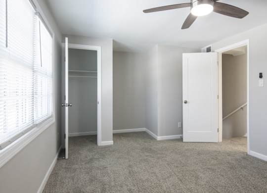 A room with a ceiling fan and a window with blinds.